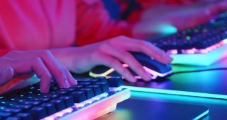 Zoomed in photo of the hands, light-up keyboards and mice of various computer game players